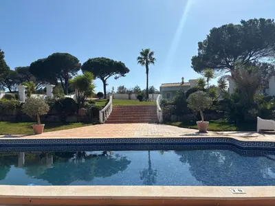 a swimming pool in a yard with trees and a house at Villa Levira with private Pool in Quarteira