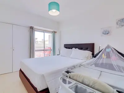 a bedroom with a large bed and a window at AL - Apartamento Wave 7 in Quarteira