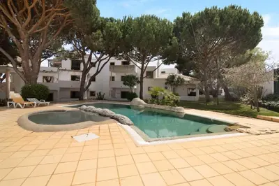 a swimming pool in a yard with trees and a building at Apartment Jardins da Falesia in Roja- Pé