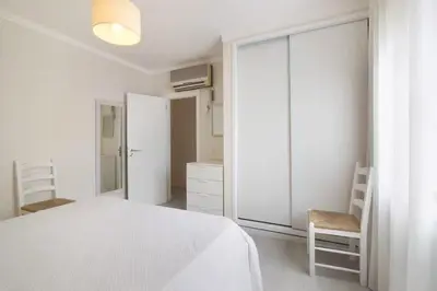 a white bedroom with a bed and a chair at Apartment Jardins da Falesia in Roja- Pé