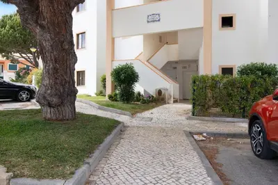 a car parked in front of a building with a tree at Apartment Jardins da Falesia in Roja- Pé