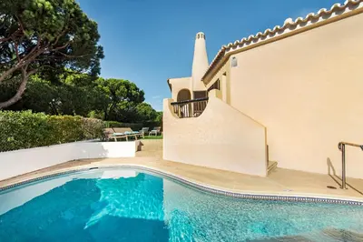 a villa with a swimming pool in front of a house at Pinhal View in Vilamoura