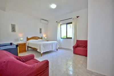 a bedroom with a bed and a red couch at Casa da Palmeira in Quarteira