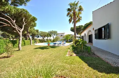 a yard with a house and a swimming pool at Casa da Palmeira in Quarteira