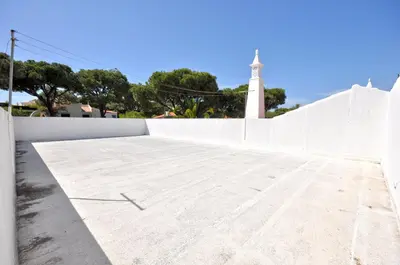 a white wall with a lighthouse in the background at Casa da Palmeira in Quarteira