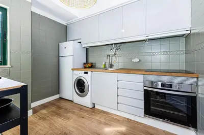 a kitchen with white cabinets and a washer and dryer at Luxury Apartment Salgados Village in Guia