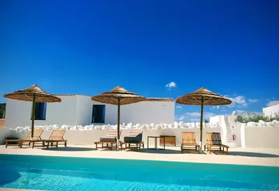 a group of chairs and umbrellas next to a swimming pool at Uma Casa Rural in Santa Bárbara de Nexe