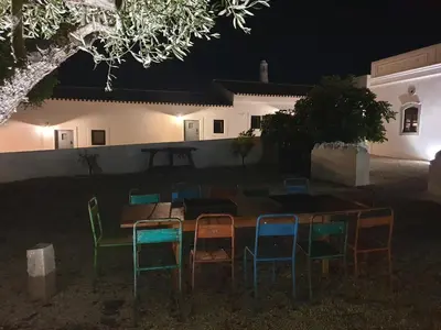 a table and chairs in front of a house at night at Uma Casa Rural in Santa Bárbara de Nexe