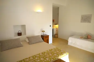 a white bedroom with two beds and a table at Uma Casa Rural in Santa Bárbara de Nexe