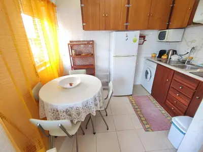 a small kitchen with a table and a refrigerator at Algarve, cozy T1plus1 apartment in the centre of Quarteira in Quarteira