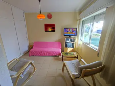 a living room with a pink bed and two chairs at Algarve, cozy T1plus1 apartment in the centre of Quarteira in Quarteira