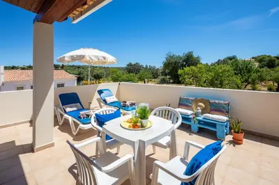 a patio with a table and chairs on a balcony at Apartamentos Casa Brito, Boliqueime by AlgarveBlossom in Boliqueime