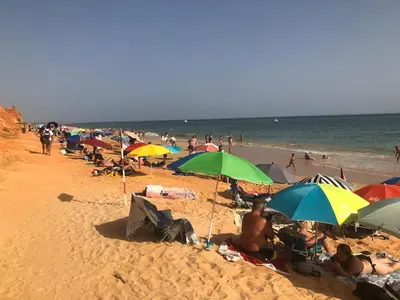 a group of people sitting on a beach with umbrellas at Casa Oura Praia located 100 metres from the beach in Albufeira