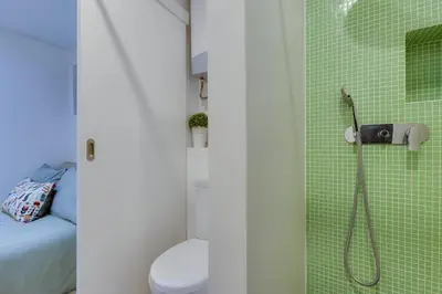 a bathroom with a shower with a toilet and green tiles at AÇOTEIAS BEACH STUDIO - 5 min to Falesia Beach in Albufeira