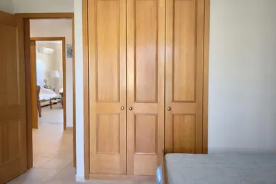 a bedroom with wooden cabinets next to a bed at Apartamento Terraços do Vale in Albufeira