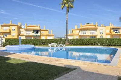 a swimming pool in front of a large building at Apartamento Terraços do Vale in Albufeira