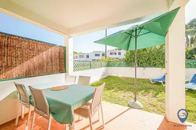 a patio with a table and a green umbrella at Balaia Mar 63A by MTPhomes in Albufeira