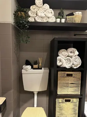 a bathroom with a toilet and a shelf with towels at Beach Holiday House T1 in Quarteira