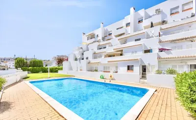 a villa with a swimming pool in front of a building at Albufeira City Centre Apartment with Pool in Albufeira
