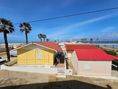 a yellow house with red roofs next to a beach at Blife Faya private apartment in FAO