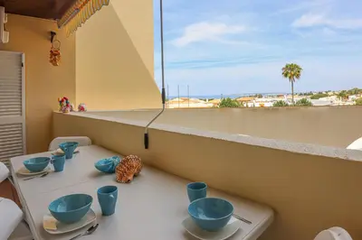a table with blue cups and bowls on a balcony at Apart Palmeira Galé - Sea view - WIFI - BY BEDZY in Guia