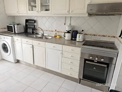 a kitchen with white cabinets and a stove top oven at Blife Allya private apartment in FAO