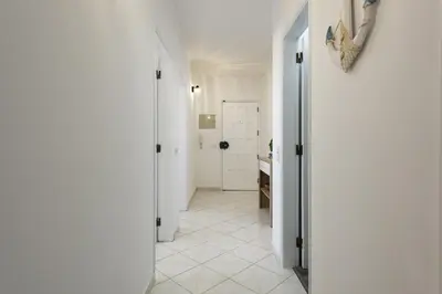a hallway with a white tile floor and a bathroom at Dunas - Sea view near the beach by HD in Quarteira