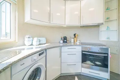 a white kitchen with a washer and dryer at Coral by MTPhomes in Albufeira