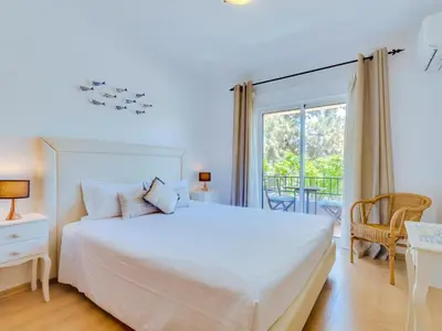 a bedroom with a large white bed and a balcony at Apartamento Mélias, 2 quartos e piscina, Vilamoura in Vilamoura