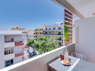 a table on a balcony with a view of a building at AL - Apartamento Mira Atlantico in Quarteira