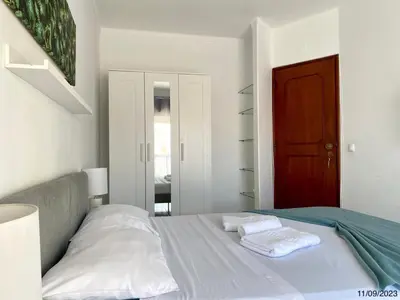 a bedroom with a bed with white sheets and a red door at Blife Anya private apartment in Faro