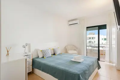 a white bedroom with a bed and a balcony at Salgados Retreat -Steps from the Beach at Homesbyfc in Guia