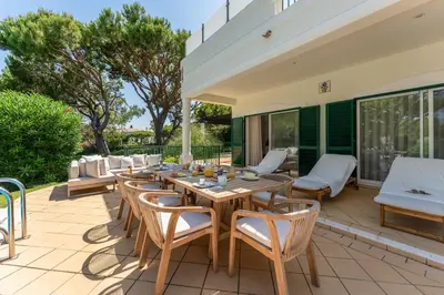 an outdoor patio with a wooden table and chairs at Villa Mia - Vale do Lobo in Vale do Lobo