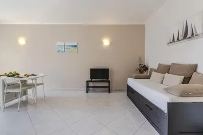 a white room with a bed and a table and a television at #344 Edificio Marina Sol by Home Holidays in Branqueira