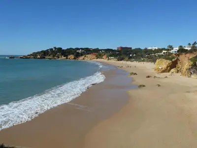 a beach with people walking on the sand and the water at Villa Jose in Olhos de Água