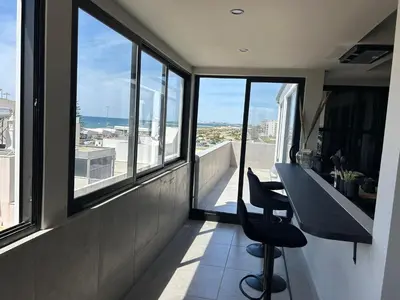 a balcony with two chairs and a table and windows at Blue Coast Penthouse T4 in Quarteira
