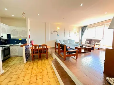 a kitchen and a living room with a table and chairs at Apartamento Gaivotas in Albufeira