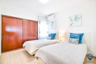 a bedroom with two beds and a wooden cabinet at Praia Mar by MTPhomes in Quarteira