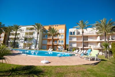 a swimming pool with palm trees and buildings at Apartamento Albufeira in Albufeira