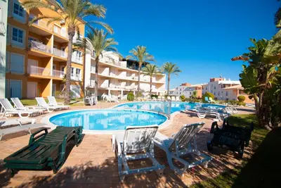 a swimming pool with chaise lounge chairs and a resort at Apartamento Albufeira in Albufeira