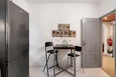 a kitchen with a table and chairs and a refrigerator at Habemus Domu Albufeira in Albufeira