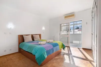 a bedroom with a large bed with colorful sheets at Habemus Domu Albufeira in Albufeira
