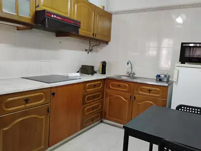 a kitchen with wooden cabinets and a white refrigerator at Cozy studio in Quarteira in Quarteira