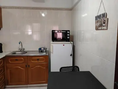 a small kitchen with a microwave on top of a refrigerator at Cozy studio in Quarteira in Quarteira