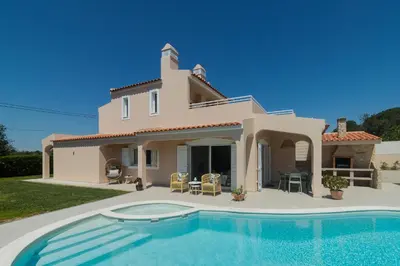 a villa with a swimming pool in front of a house at Villa Juliet in Boliqueime