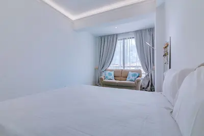 a white bedroom with a bed and a chair at Carteia Beachfront at Praia da Gaivota in Quarteira