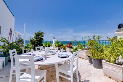 a white table and chairs on a patio with the ocean at Carteia Beachfront at Praia da Gaivota in Quarteira