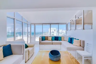 a living room with white furniture and large windows at Carteia Beachfront at Praia da Gaivota in Quarteira