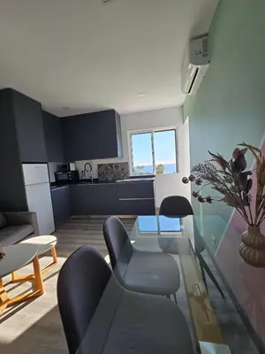 a living room with a glass table and a kitchen at O Forte by MTPhomes in Albufeira