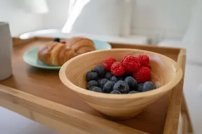 a wooden bowl with raspberries and blueberries on a table at Panoramic Sea Views & Balcony BBQ by HostWise in Albufeira